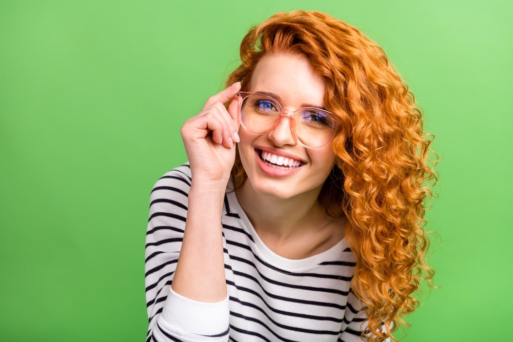 Pretty red-headed woman has nice eyeglasses frames after trying on a wide selection.