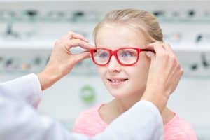 Nearsighted kid tries on new red glasses to improve her vision